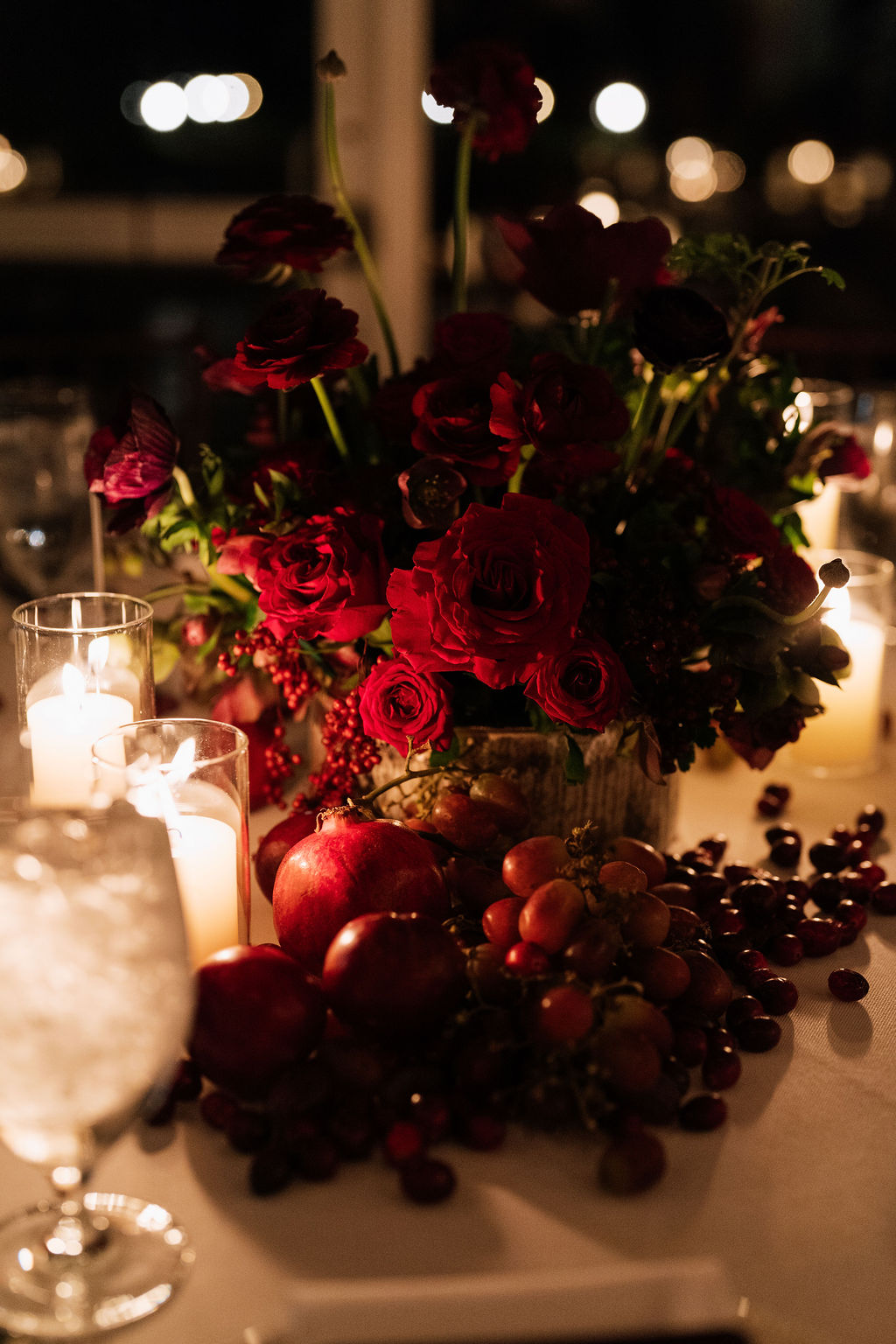 Candlelit winter wedding tablescape at Saltwater Farm in Stonington, Connecticut with silver compotes, fresh fruit, oxblood pillar candles, and moody florals.