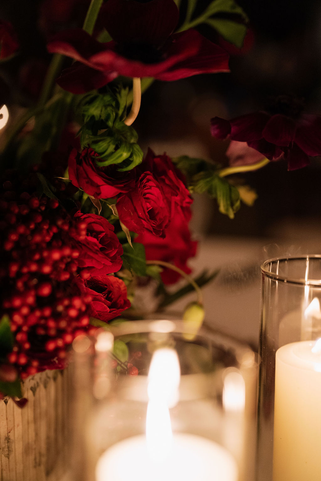 Moody winter wedding reception at Saltwater Farm Vineyard in Stonington, Connecticut with burgundy and plum florals, evergreens, pomegranate, and pillar candles.